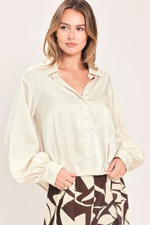 A woman wearing a champagne-colored satin long-sleeve blouse with a button-down front | Flying Tomato