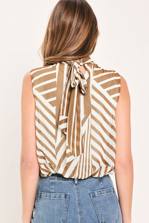 Woman wearing a sleeveless mocha and white geometric striped top with a high neck and flow silhouette | Flying Tomato