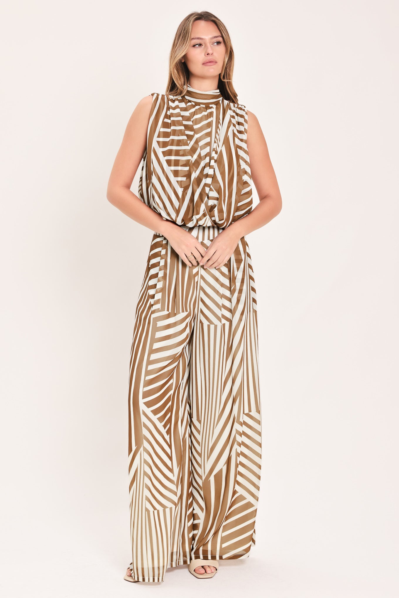 Woman wearing a sleeveless mocha and white geometric striped top with a high neck and flow silhouette | Flying Tomato