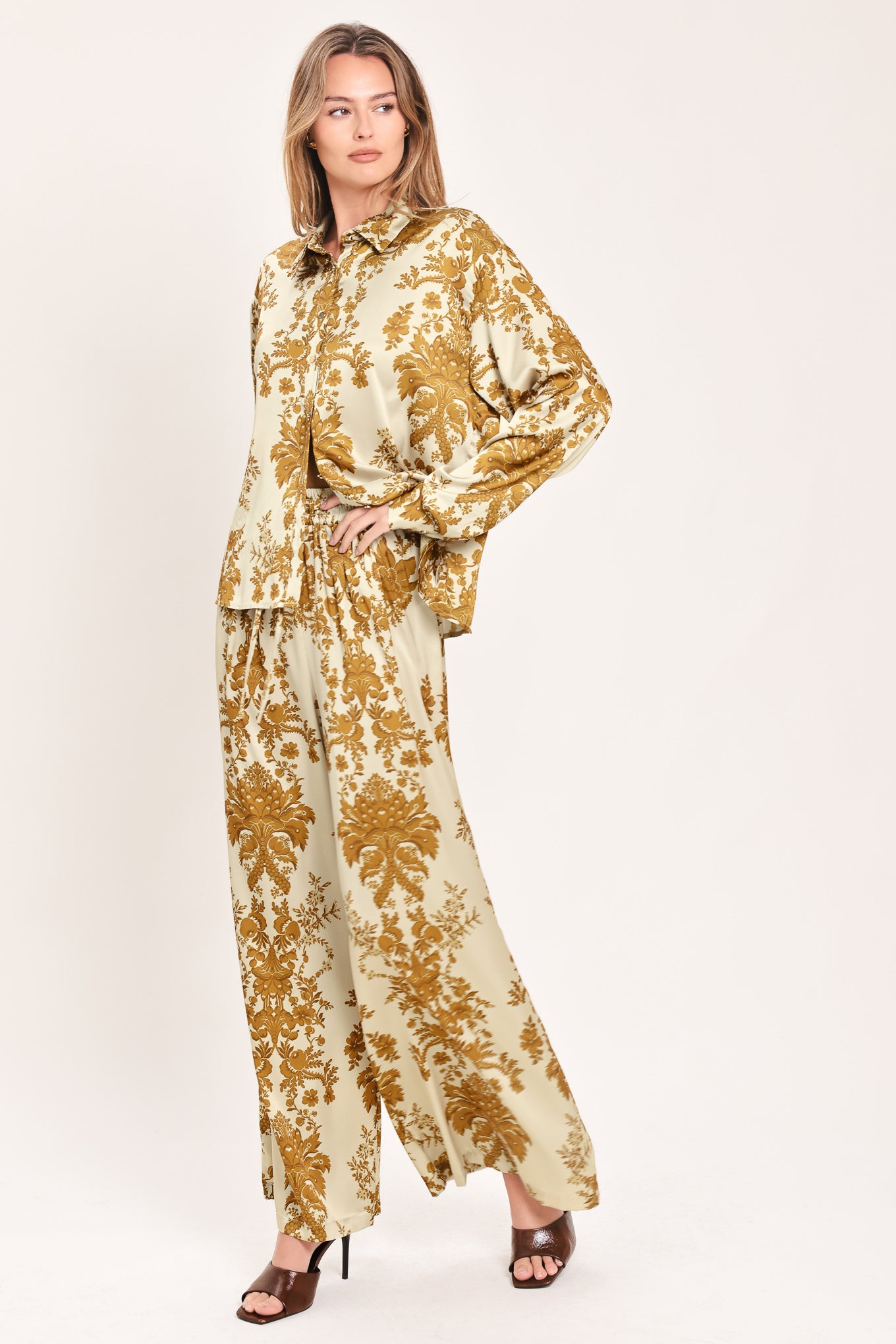 A woman wearing a long-sleeve button-up blouse with a beige and gold damask pattern | Flying Tomato