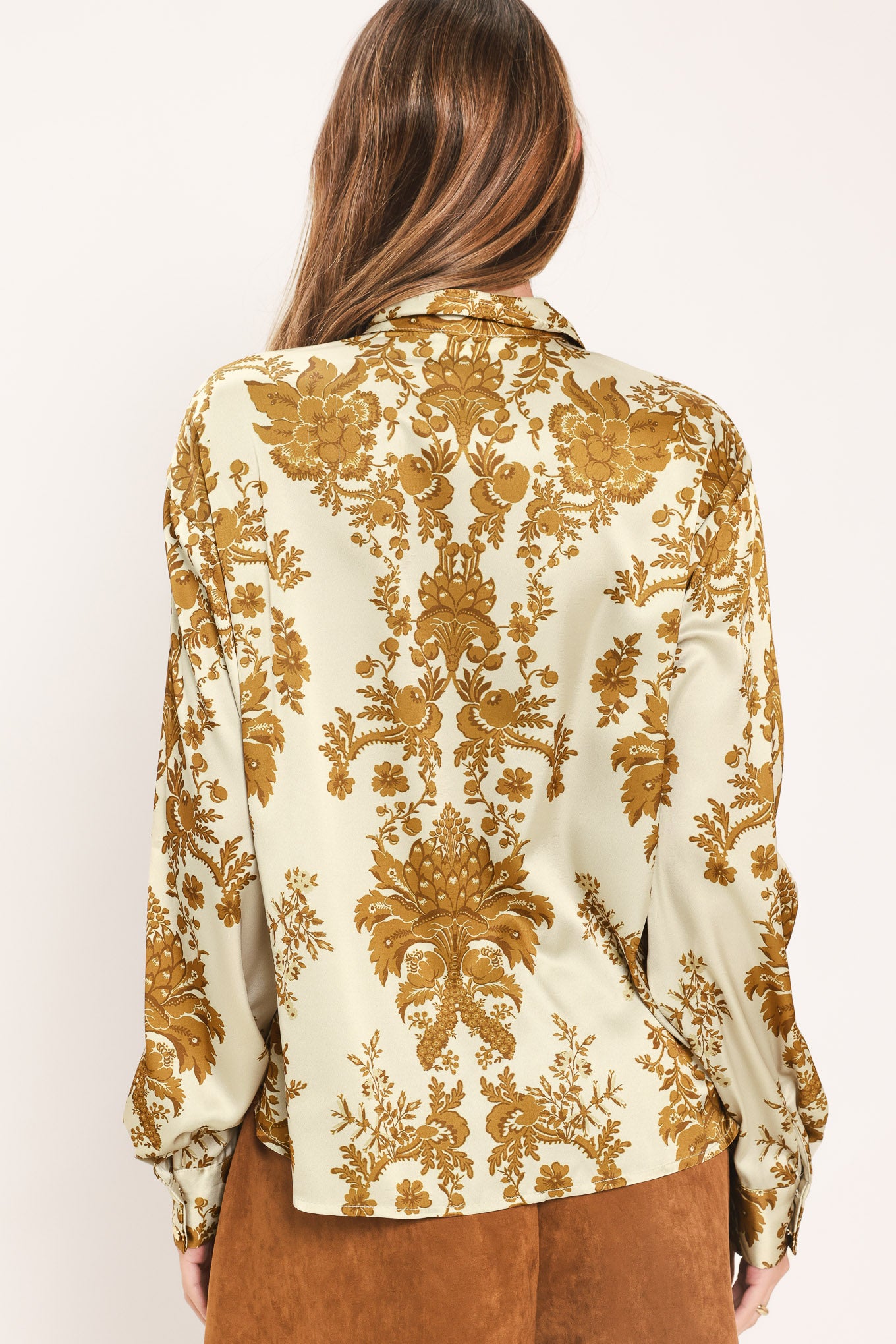 A woman wearing a long-sleeve button-up blouse with a beige and gold damask pattern | Flying Tomato