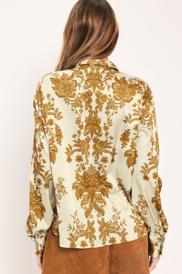 A woman wearing a long-sleeve button-up blouse with a beige and gold damask pattern | Flying Tomato