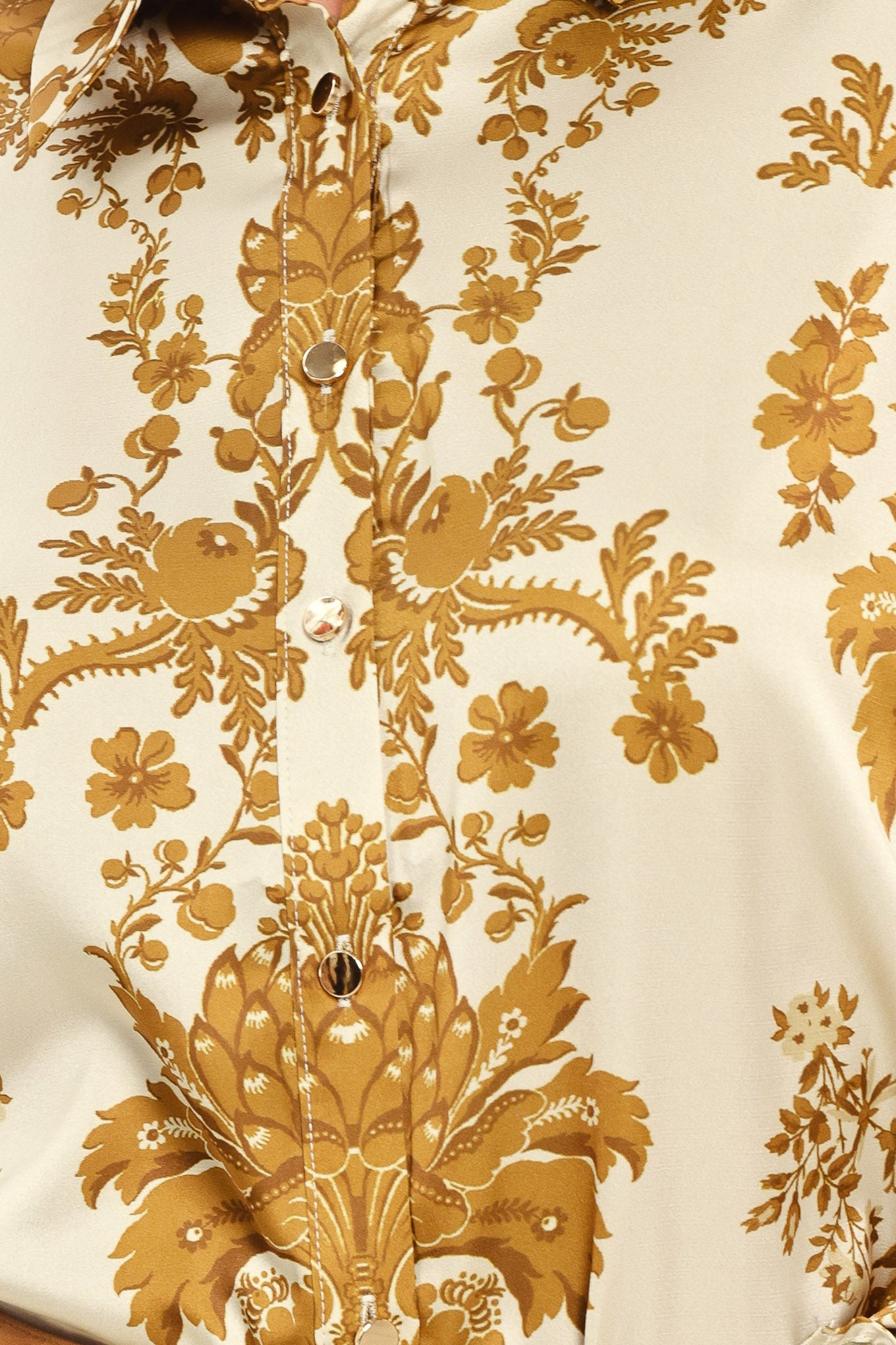 A woman wearing a long-sleeve button-up blouse with a beige and gold damask pattern | Flying Tomato