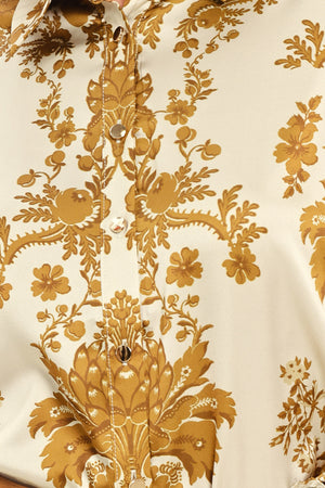 A woman wearing a long-sleeve button-up blouse with a beige and gold damask pattern | Flying Tomato