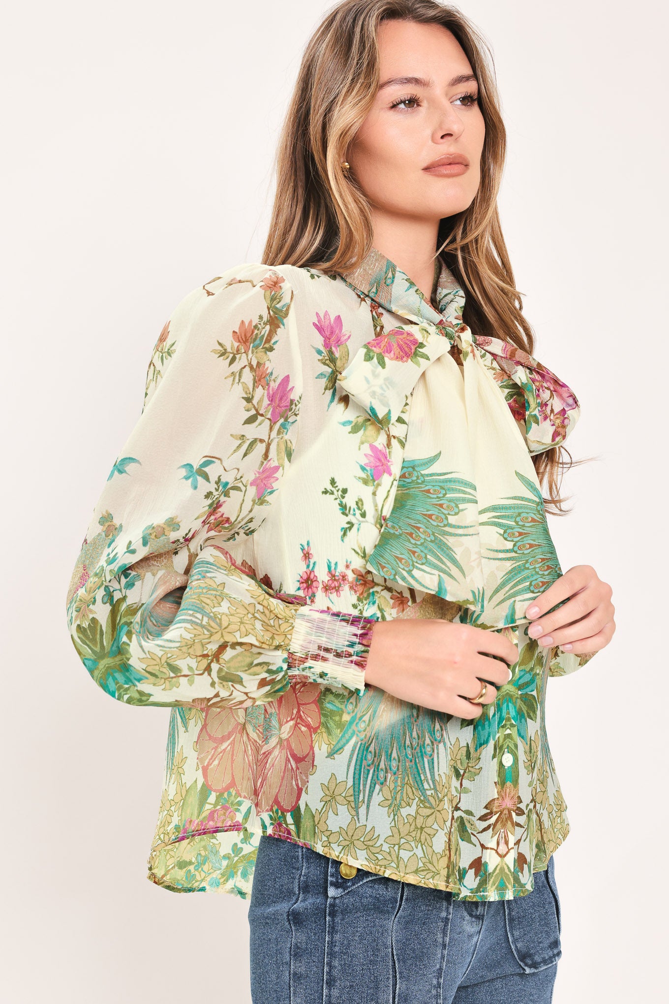 A woman wearing a long-sleeve blouse with a large bow at the collar and a tropical floral print | Flying Tomato