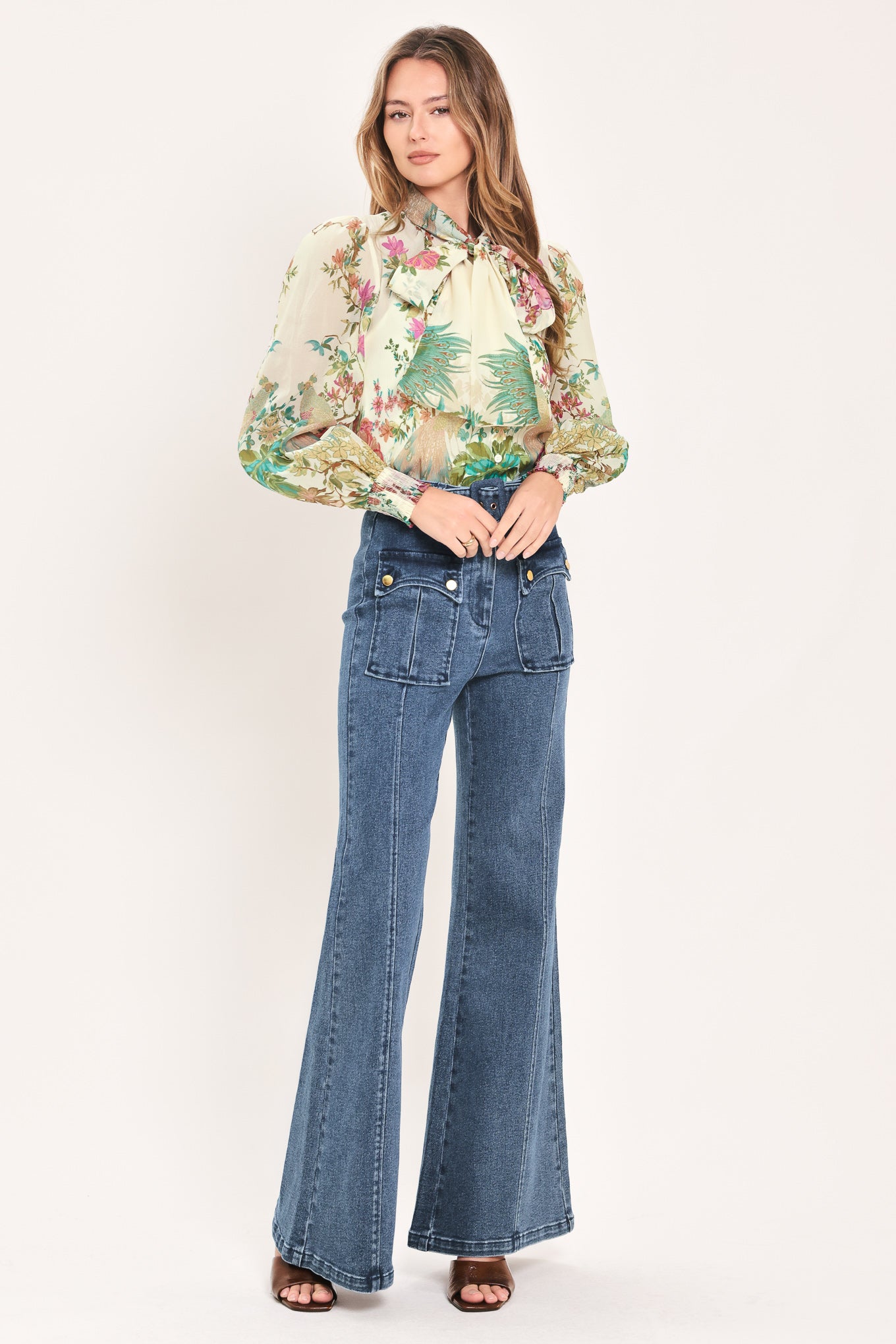 A woman wearing a long-sleeve blouse with a large bow at the collar and a tropical floral print | Flying Tomato