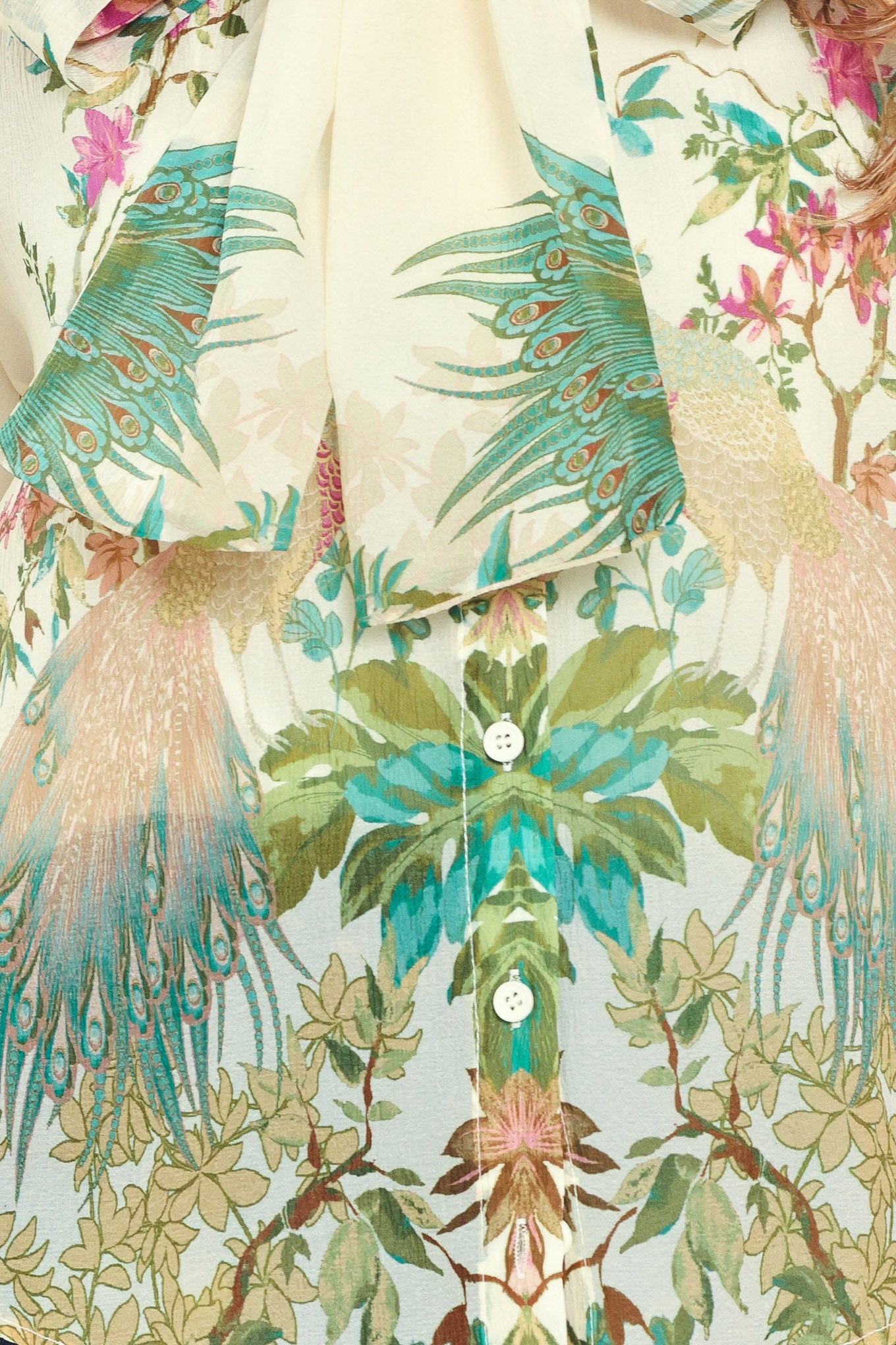 A woman wearing a long-sleeve blouse with a large bow at the collar and a tropical floral print | Flying Tomato
