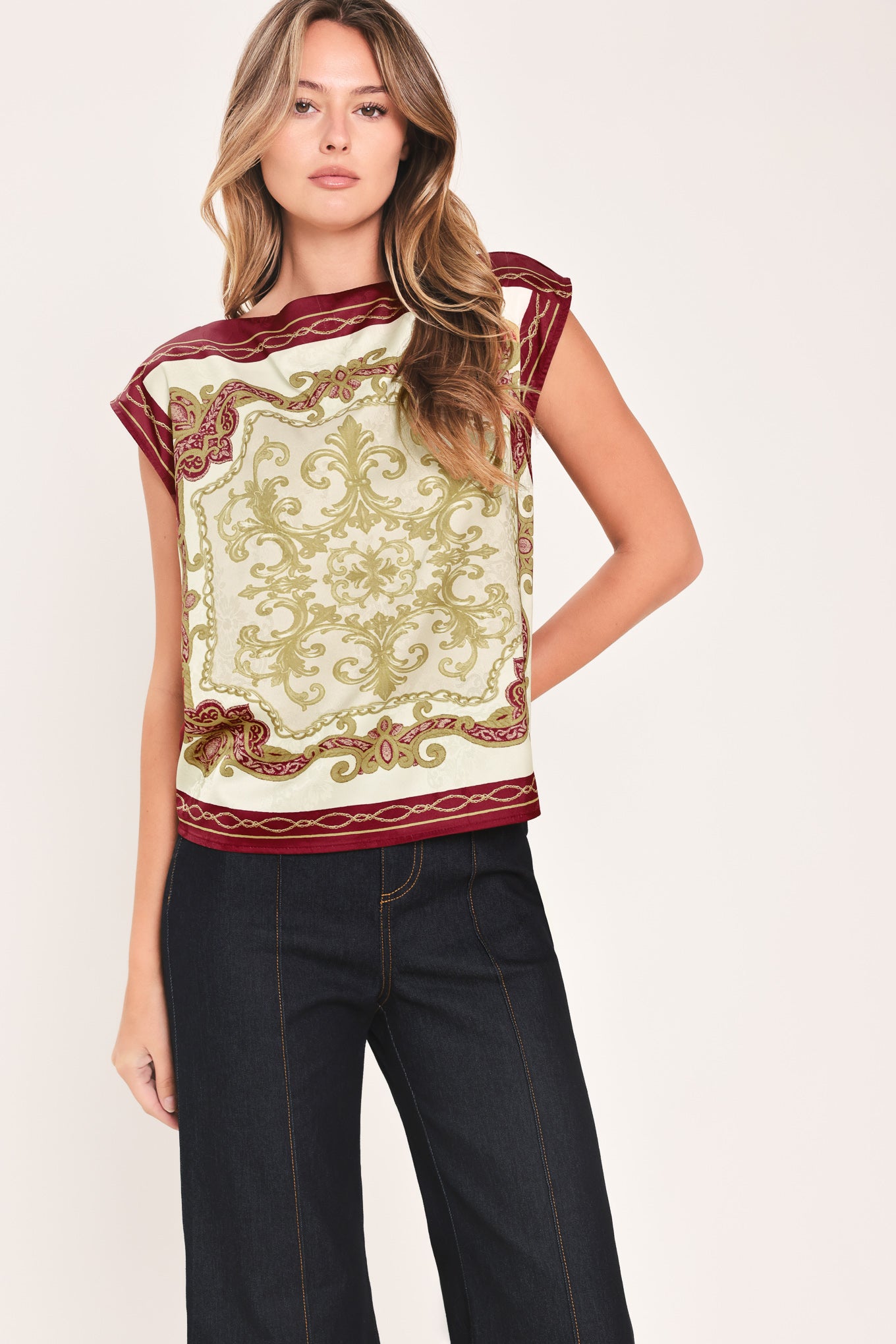 A woman wearing a sleeveless top with a cream base and ornate burgundy and olive-gold baroque-style border and damask pattern | Flying Tomato