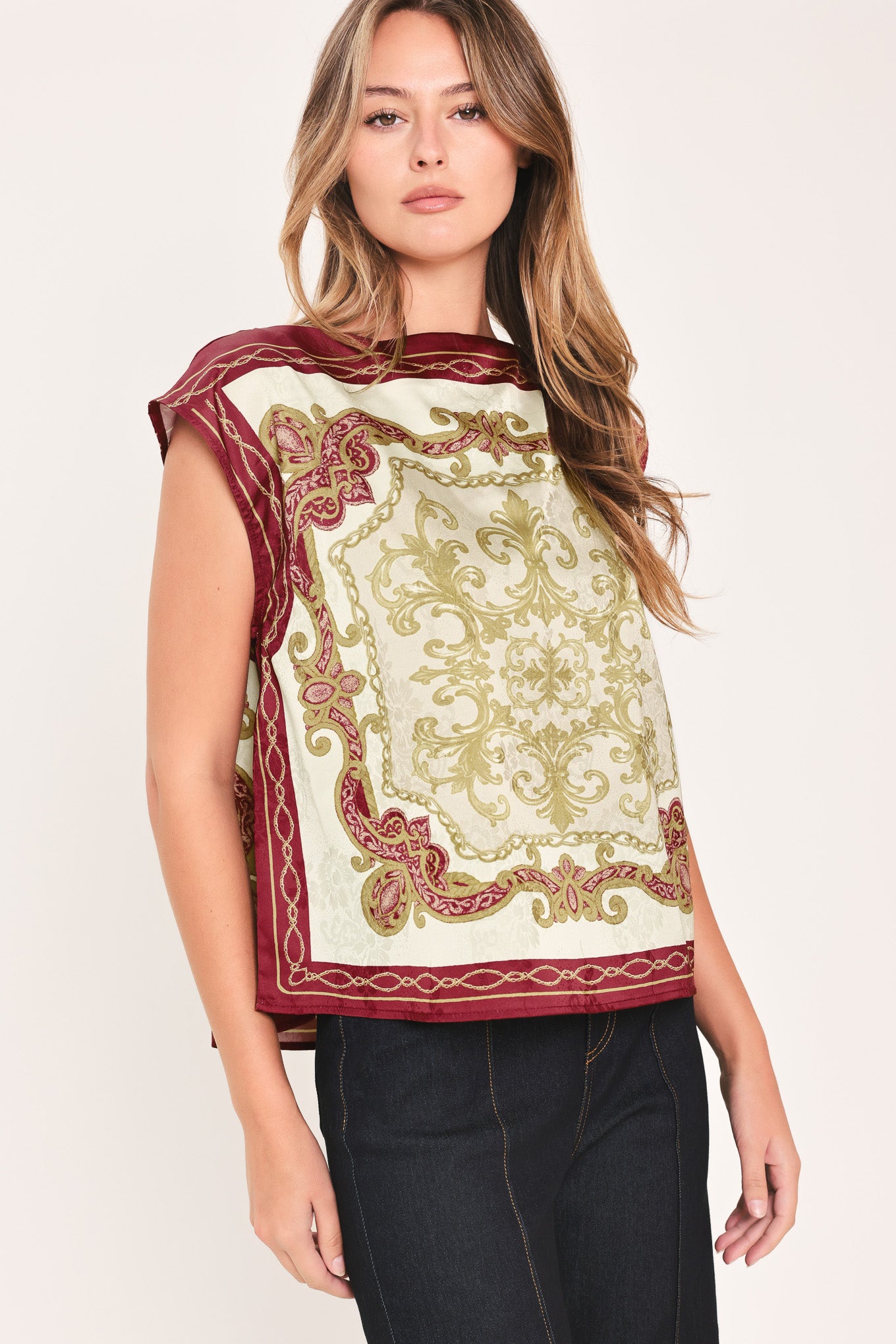 A woman wearing a sleeveless top with a cream base and ornate burgundy and olive-gold baroque-style border and damask pattern | Flying Tomato