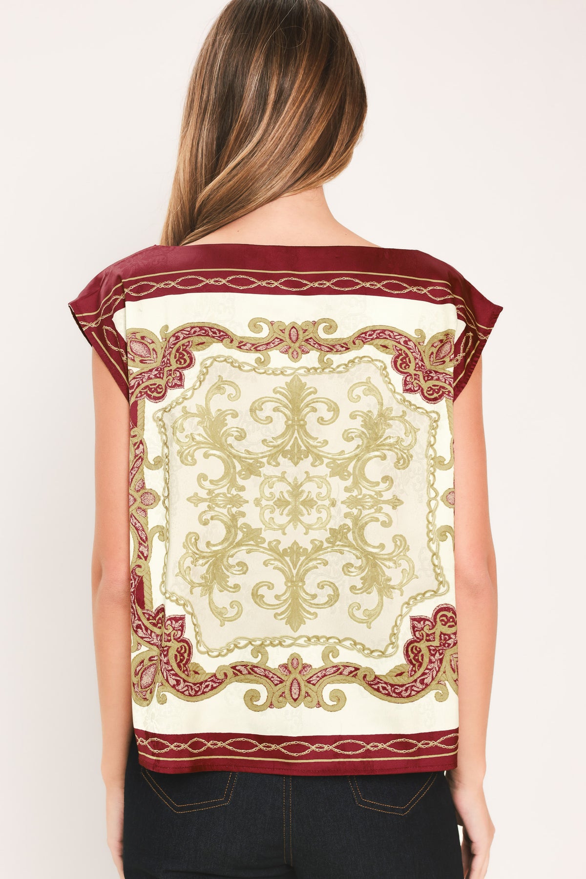 A woman wearing a sleeveless top with a cream base and ornate burgundy and olive-gold baroque-style border and damask pattern | Flying Tomato
