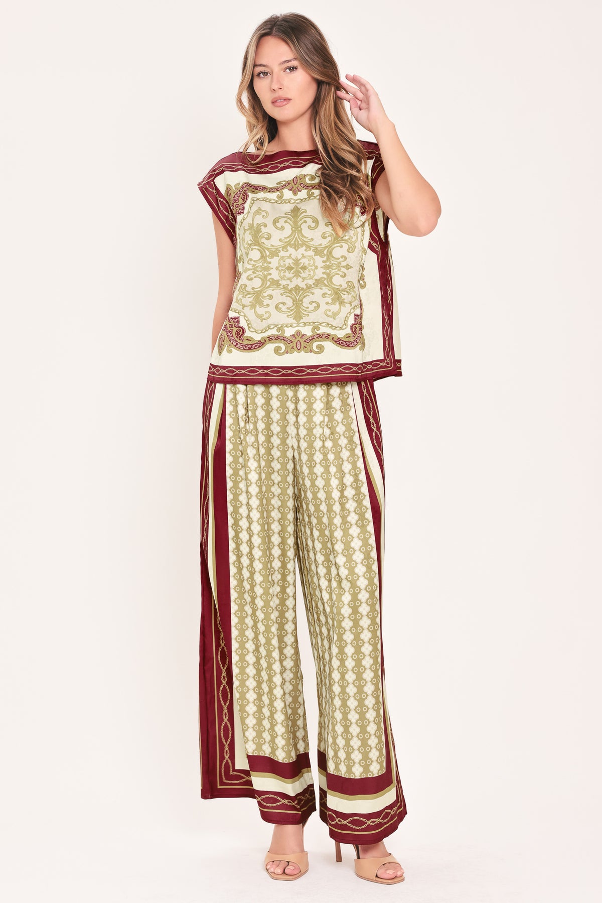 A woman wearing a sleeveless top with a cream base and ornate burgundy and olive-gold baroque-style border and damask pattern | Flying Tomato