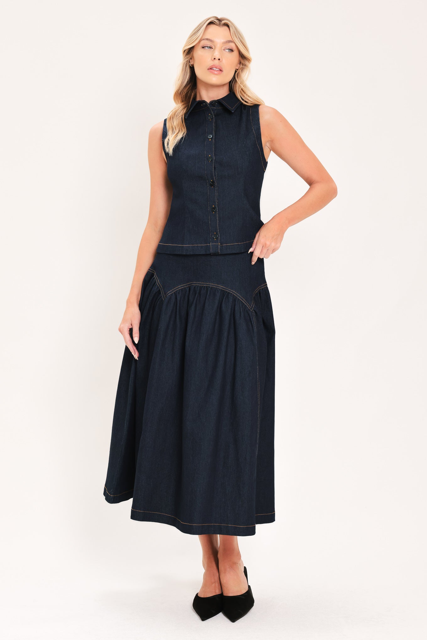 A woman modeling a sleeveless dark denim top and midi skirt  with a button-front bodice, pointed collar, and a gathered skirt | Flying Tomato