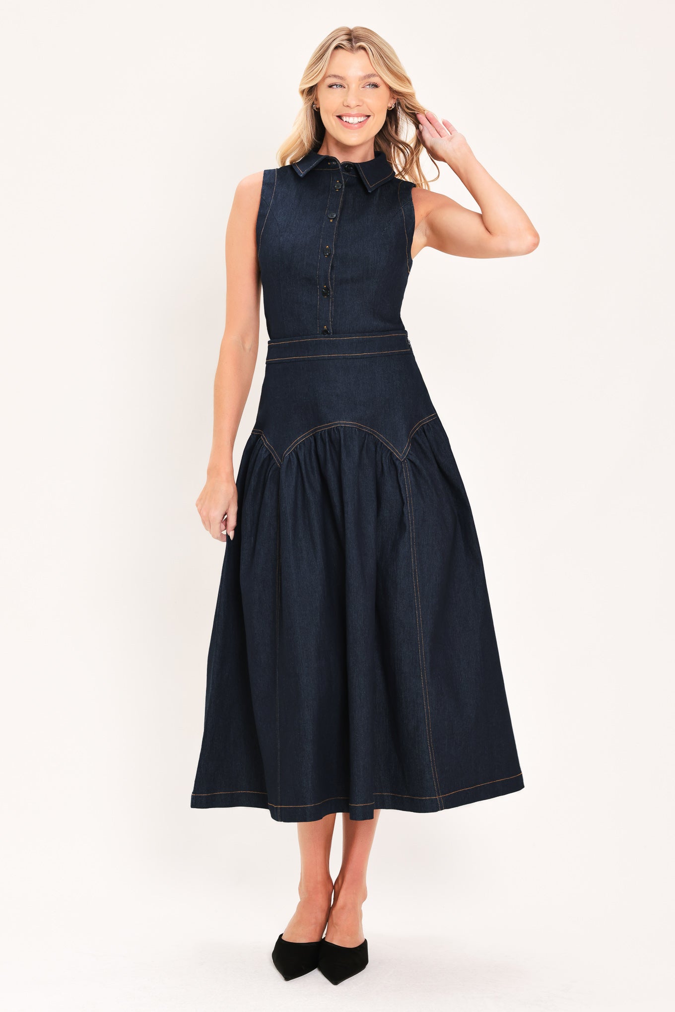 A woman modeling a sleeveless dark denim top and midi skirt  with a button-front bodice, pointed collar, and a gathered skirt | Flying Tomato