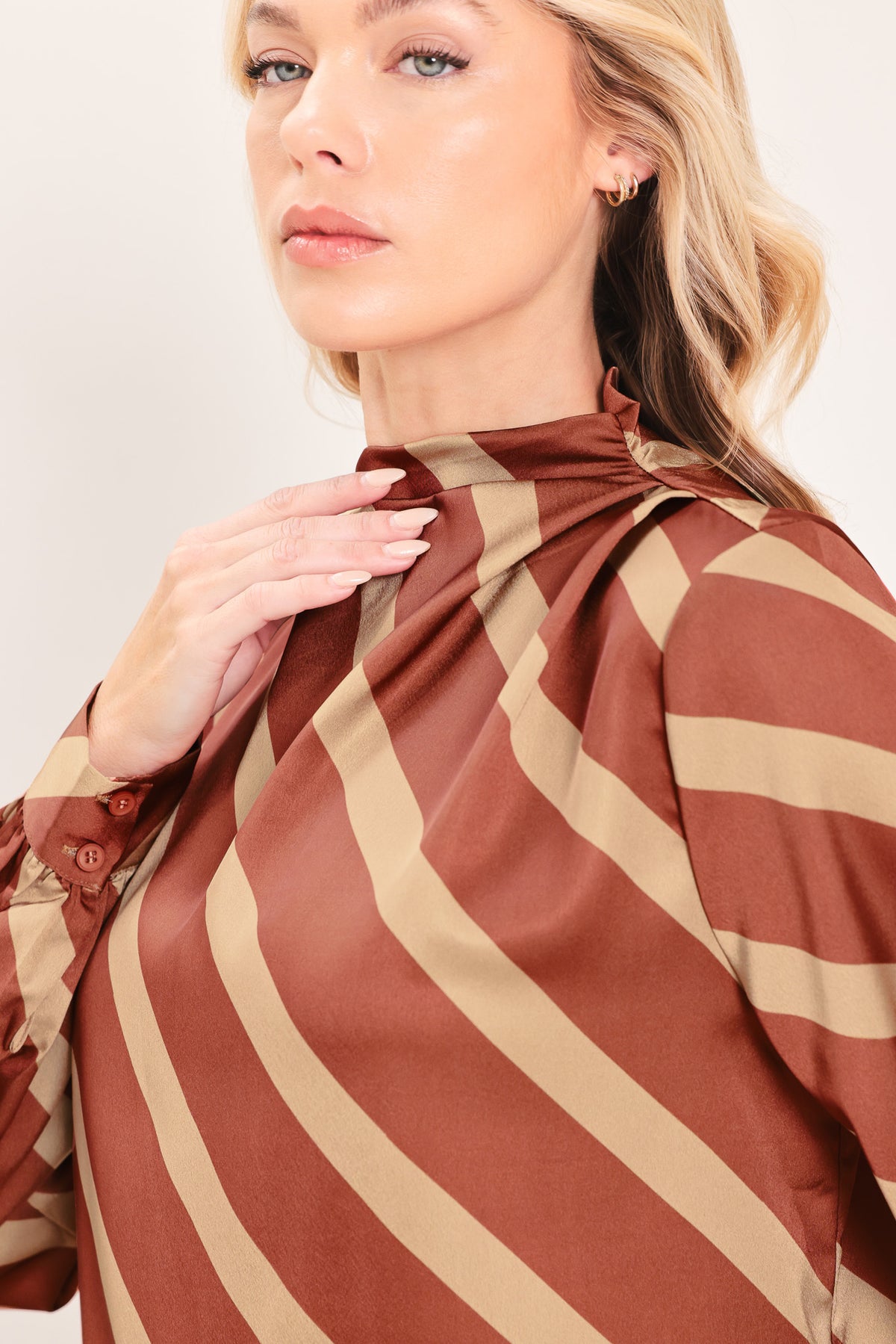 A woman wearing a brown and beige diagonally striped satin blouse with long balloon sleeves | Flying Tomato