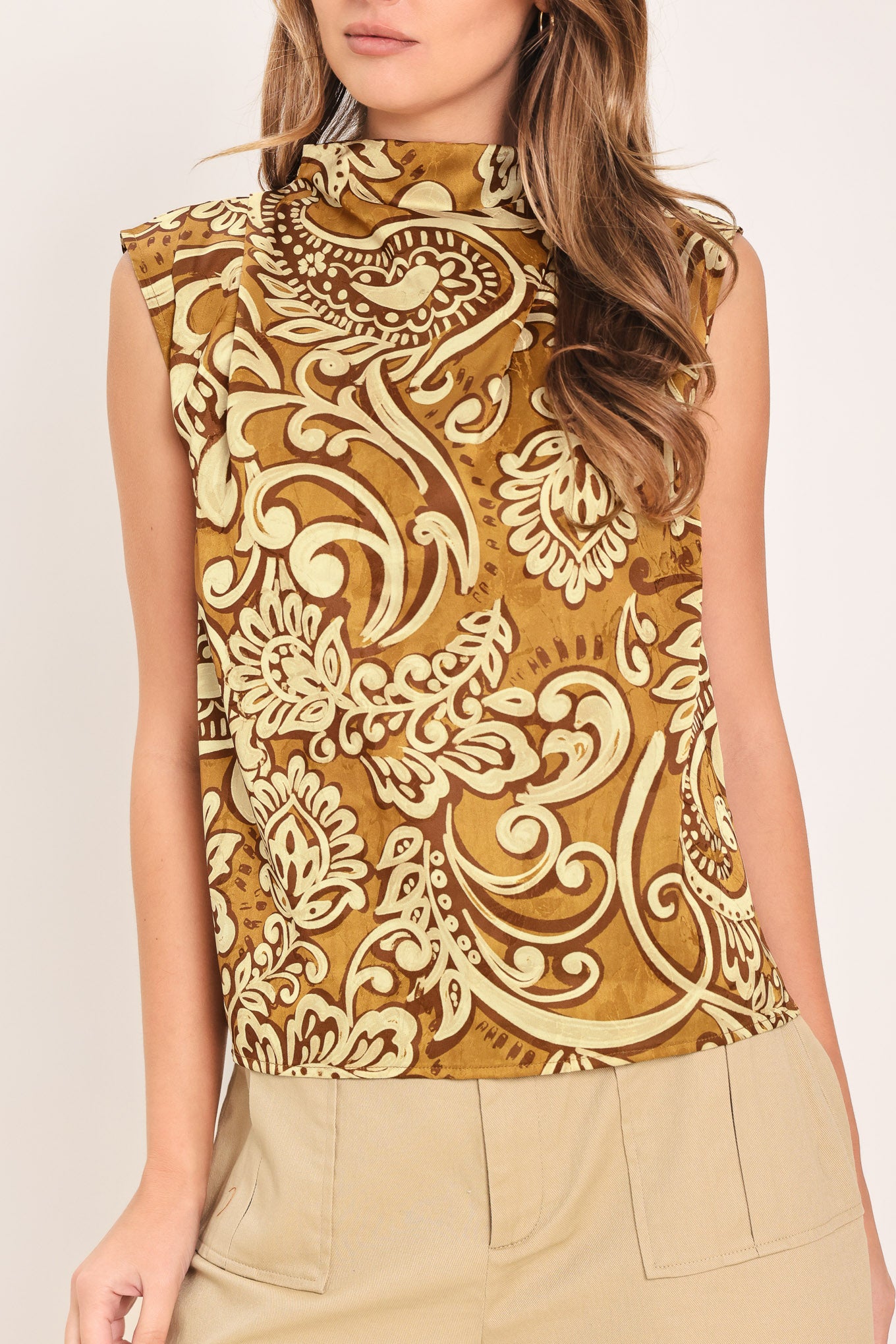 Woman wearing a sleeveless brown multi-toned printed woven top with funnel neckline and back zipper closure | Flying Tomato