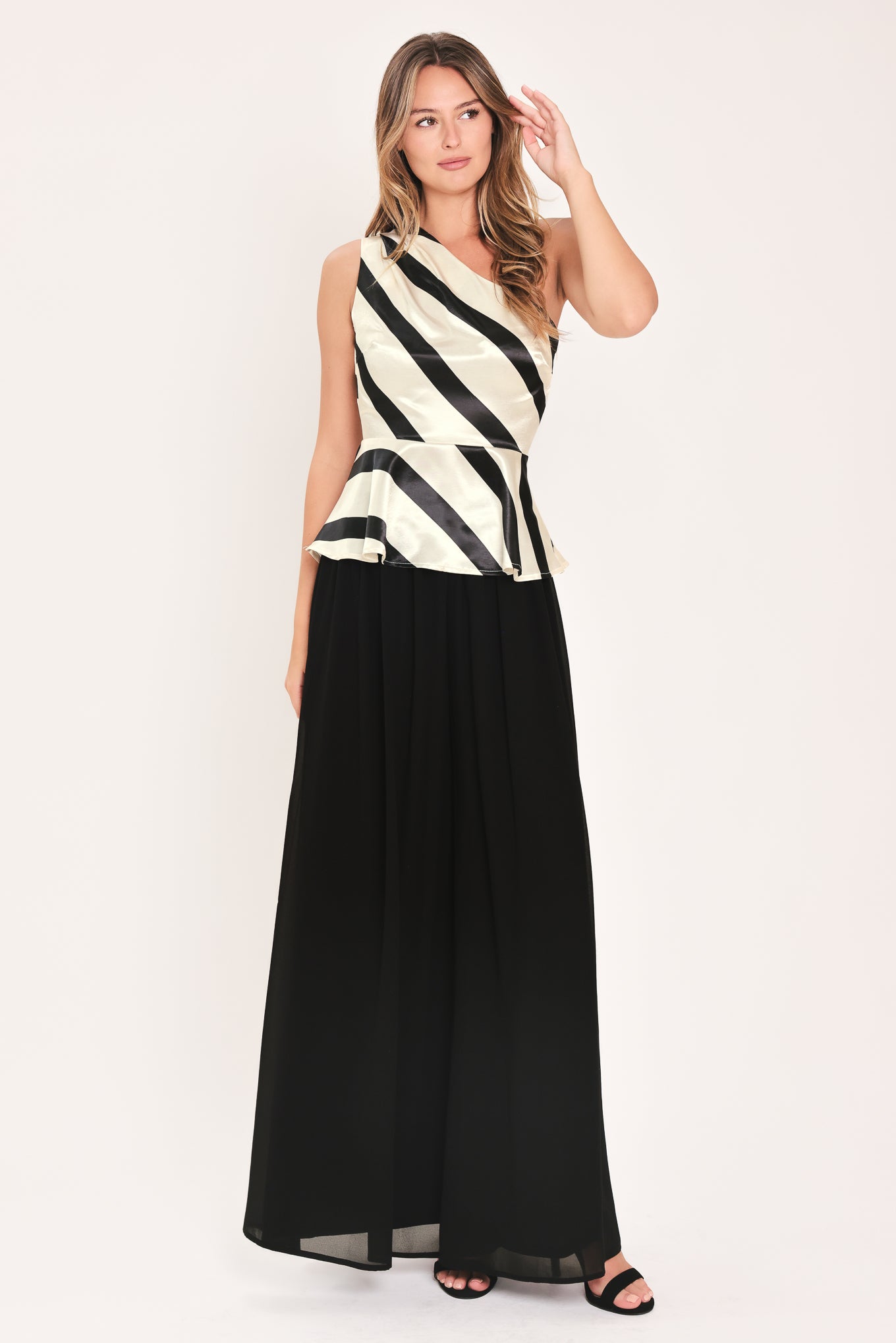 A woman modeling a sleeveless one-shoulder peplum top with diagonal black and cream satin-like stripes | Flying Tomato