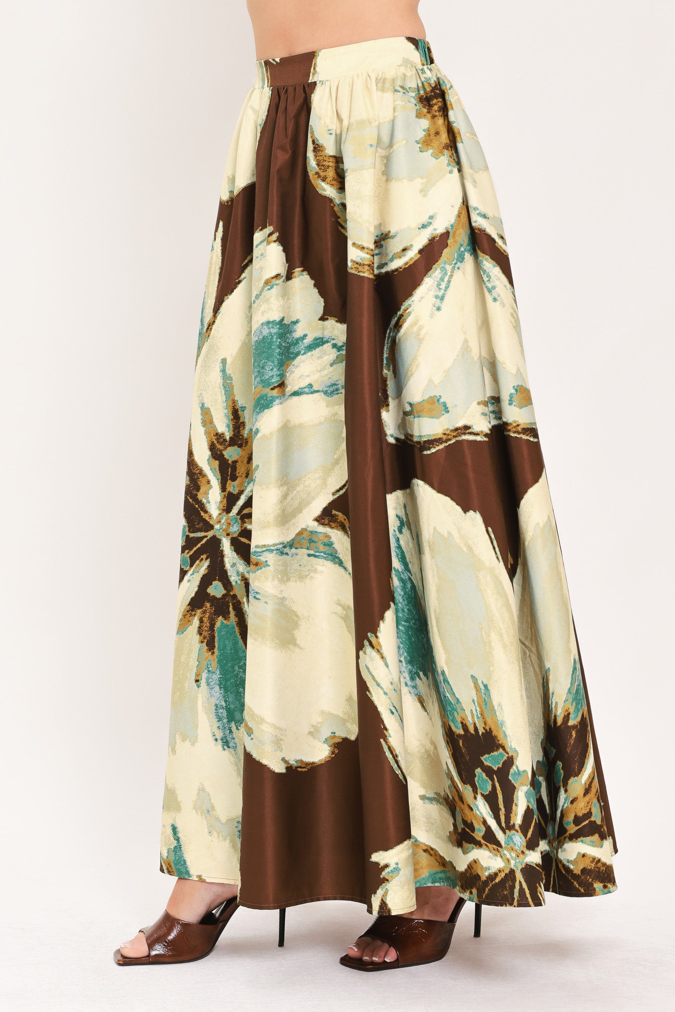 A woman modeling a sleeveless top and  matching maxi skirt with a brown and cream floral print and teal accents | Flying Tomato