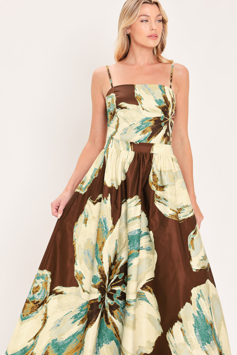 A woman modeling a sleeveless top and  matching maxi skirt with a brown and cream floral print and teal accents | Flying Tomato