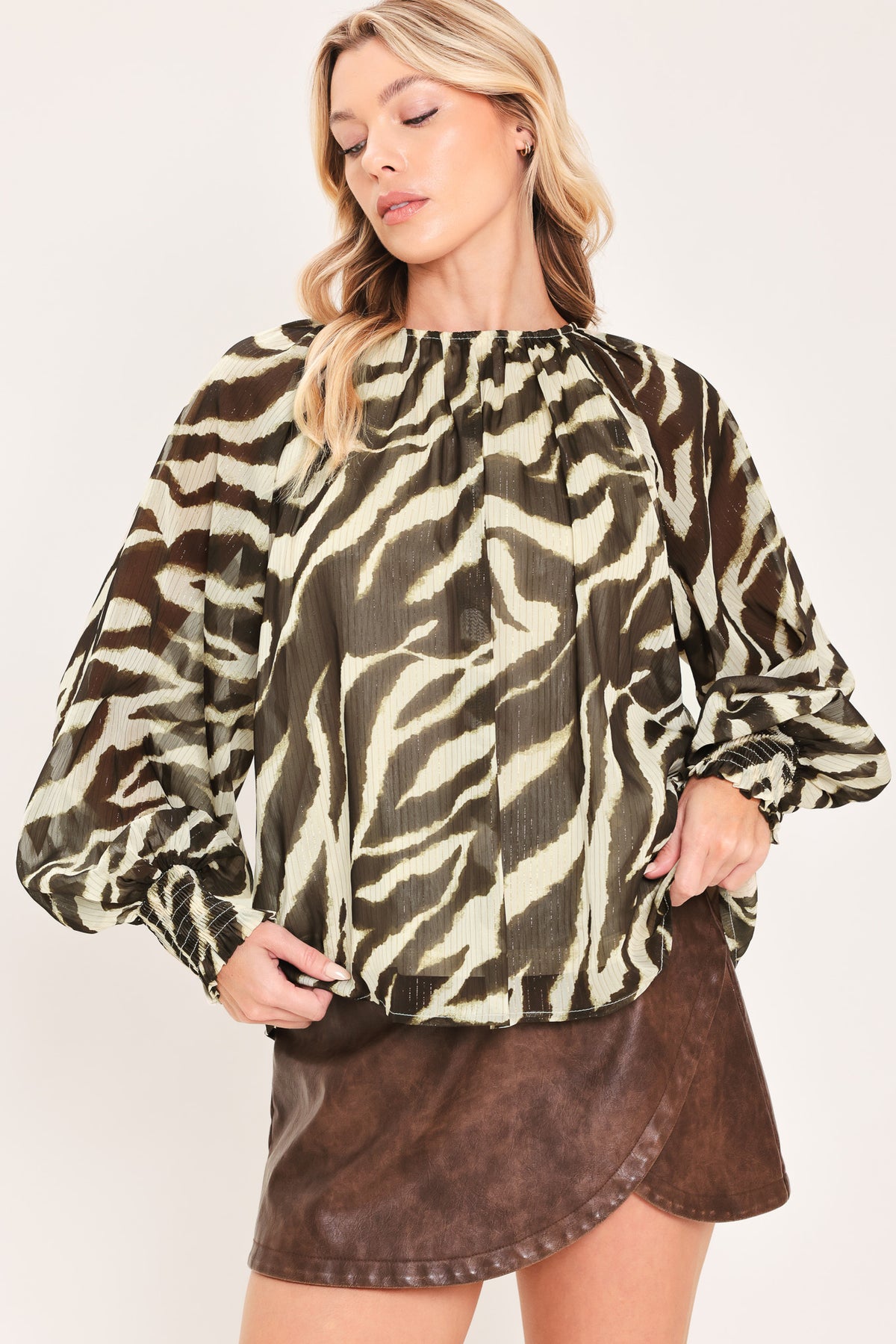 A woman wearing a dark brown and beige zebra-print blouse with voluminous long sleeves and a gathered neckline | Flying Tomato