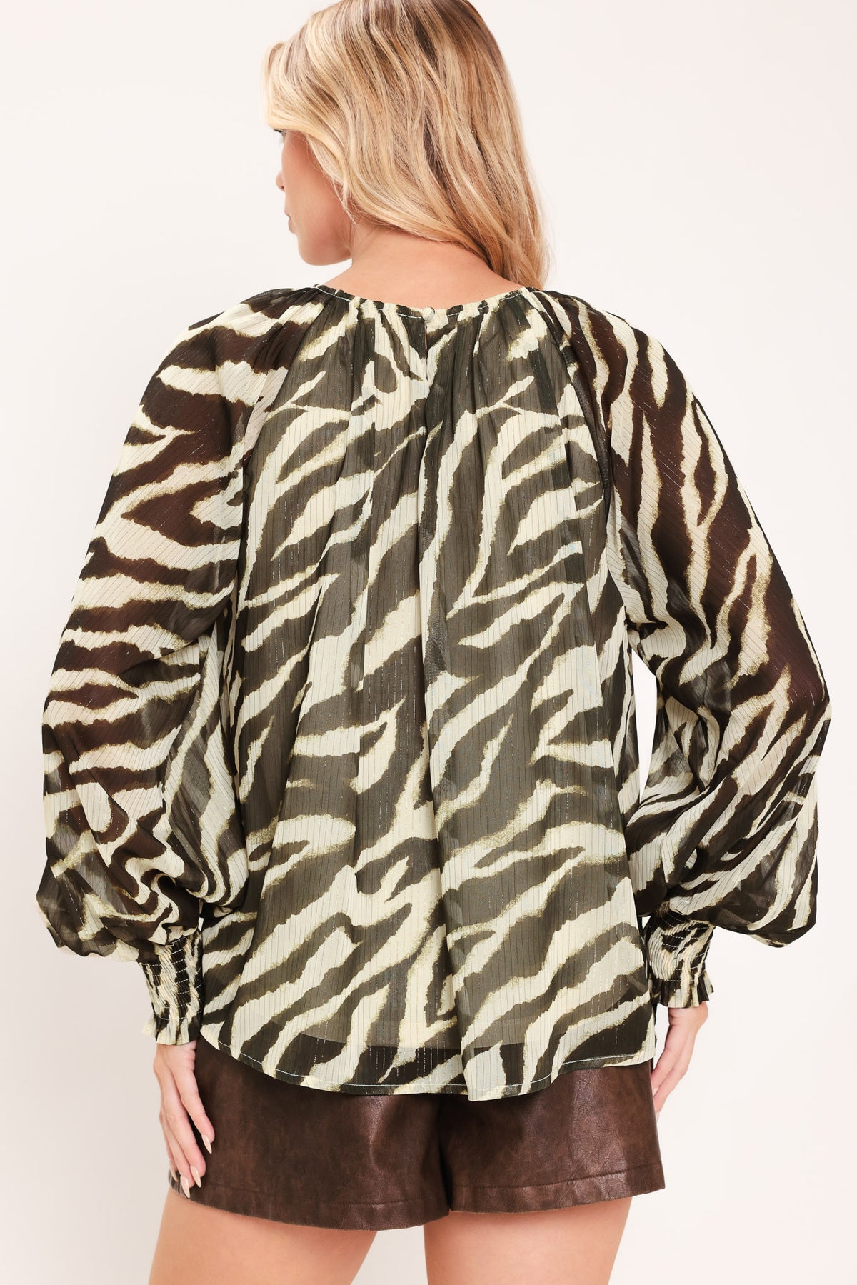 A woman wearing a dark brown and beige zebra-print blouse with voluminous long sleeves and a gathered neckline | Flying Tomato