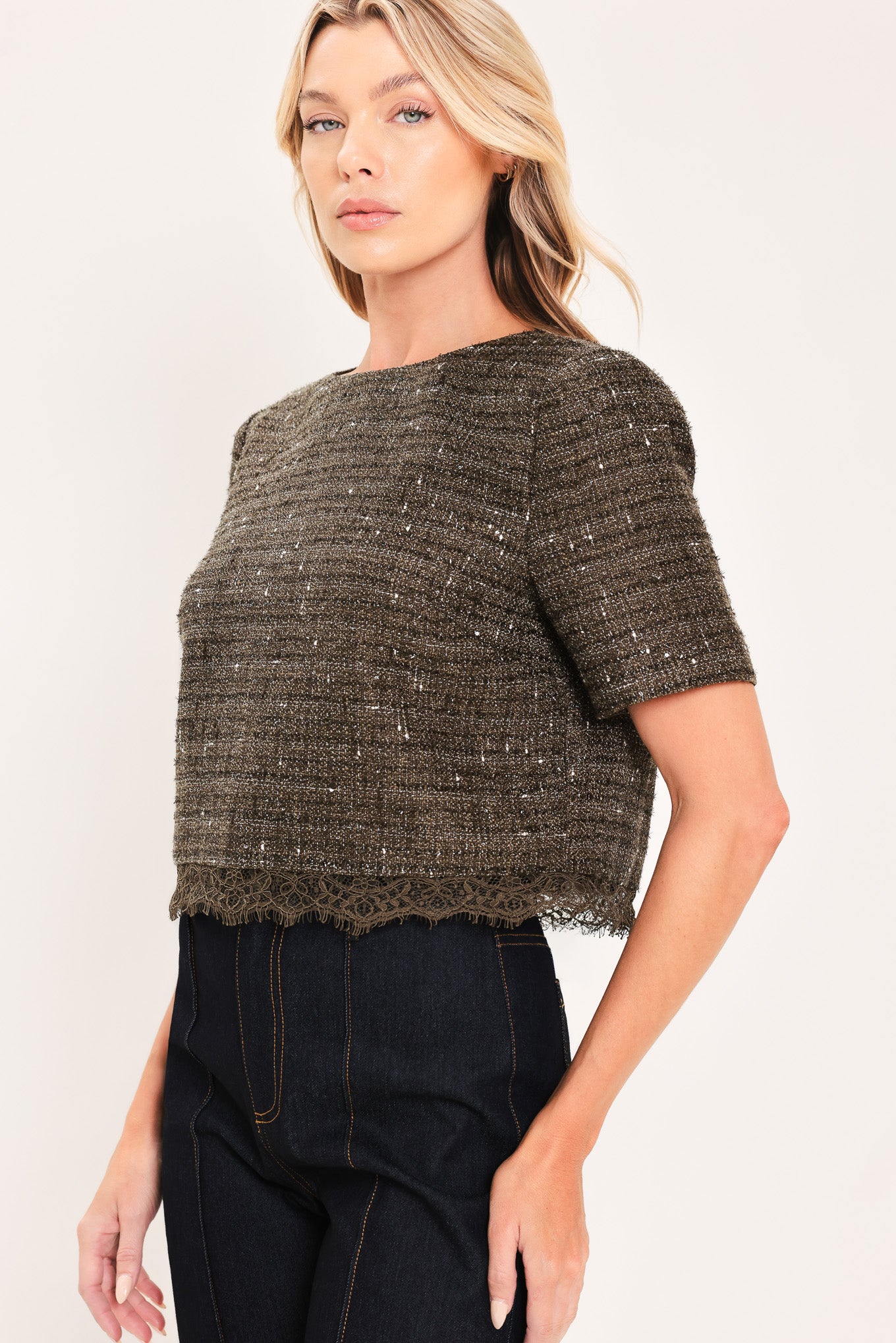 A woman wearing a short-sleeve textured tweed top in dark dark khaki with subtle silver flecks | Flying Tomato