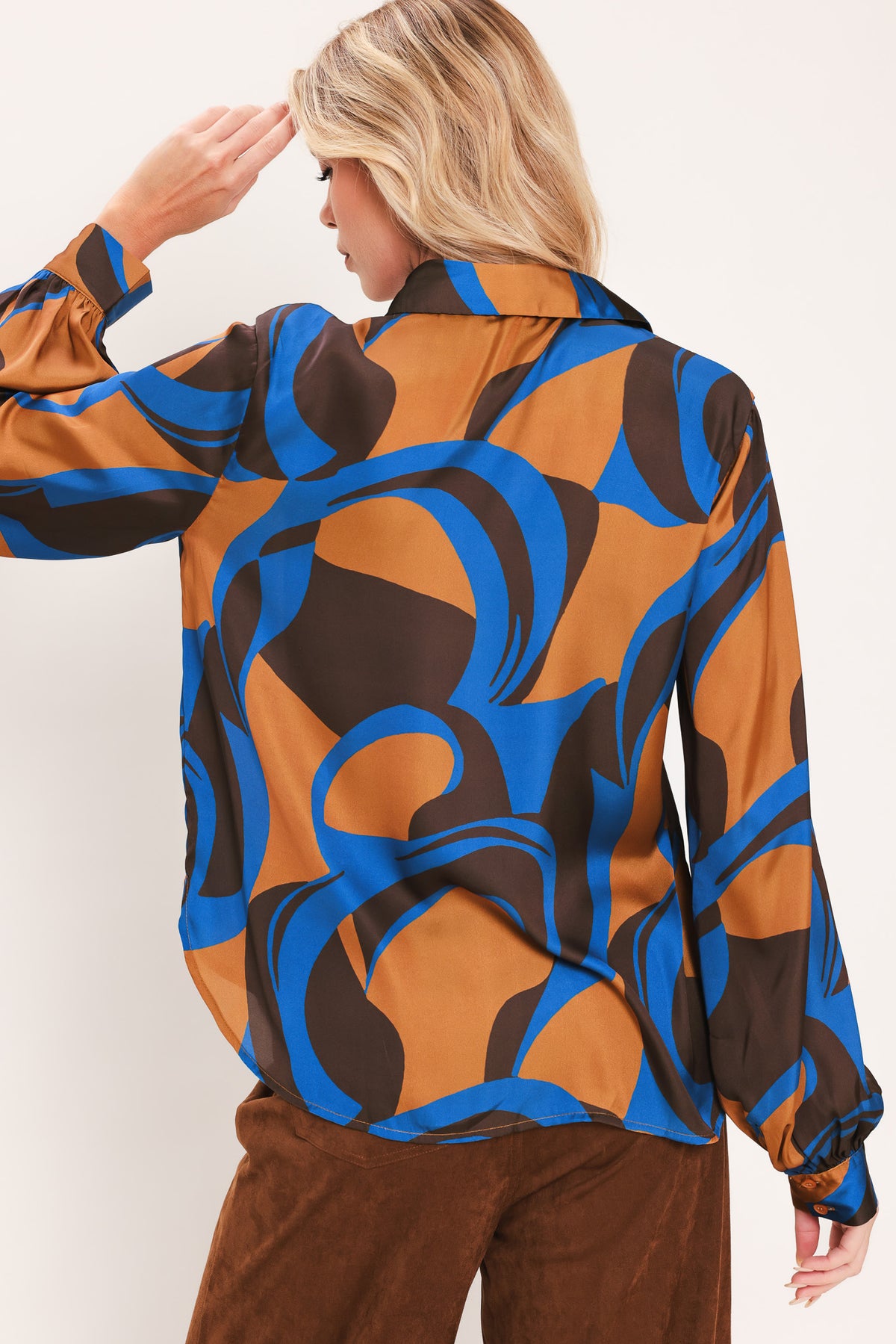 A woman modeling a long-sleeve button-up shirt with an abstract wavy pattern in brown, blue, and black | Flying Tomato