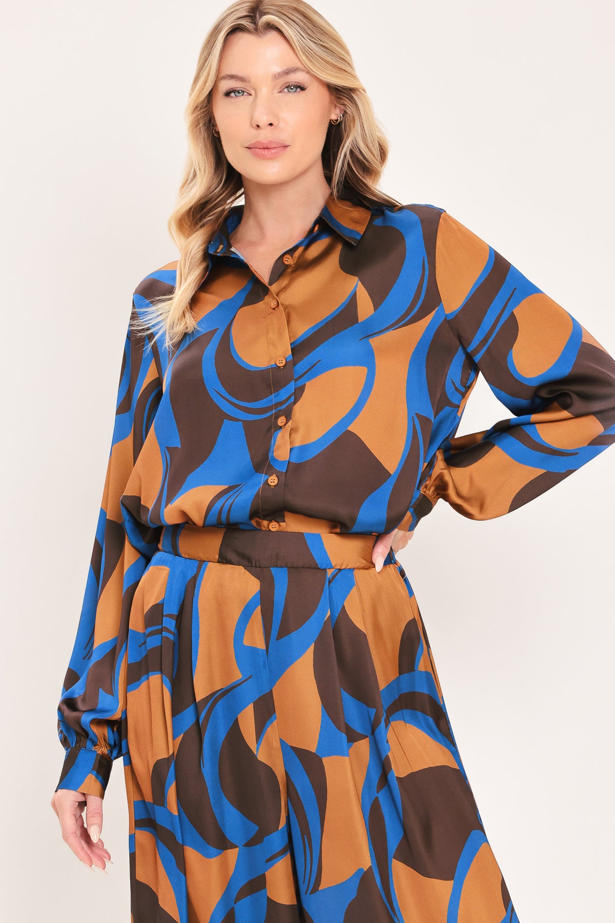 A woman modeling a long-sleeve button-up shirt with an abstract wavy pattern in brown, blue, and black | Flying Tomato