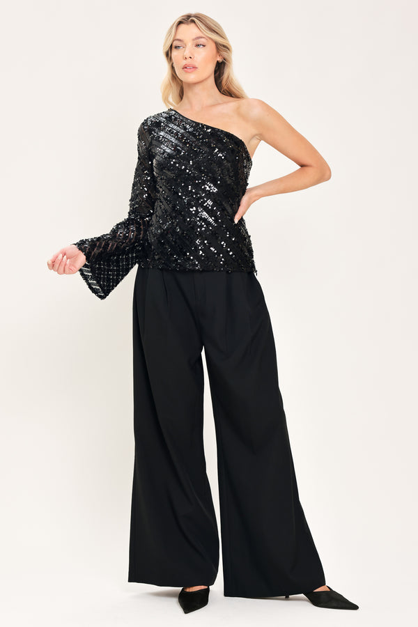 A woman modeling a black one-shoulder sequined top with long bell sleeves | Flying Tomato