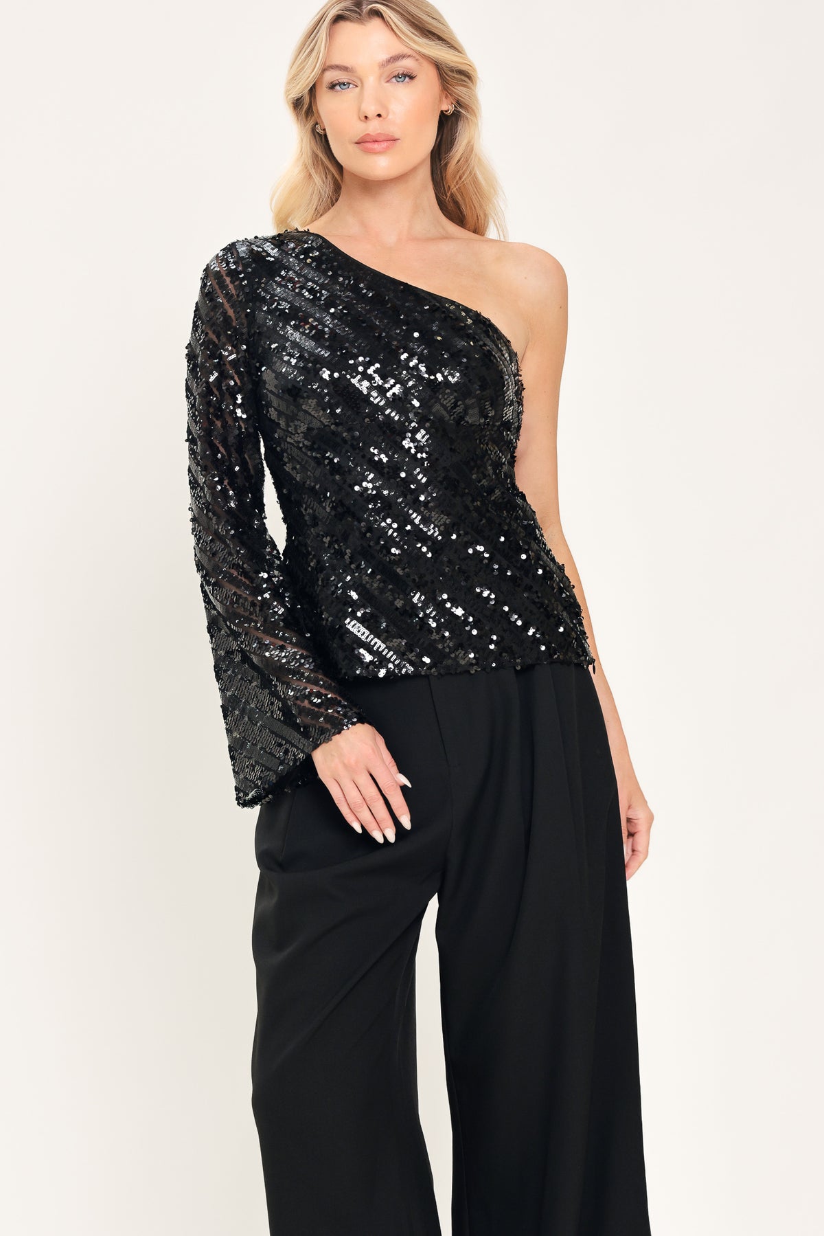 A woman modeling a black one-shoulder sequined top with long bell sleeves | Flying Tomato