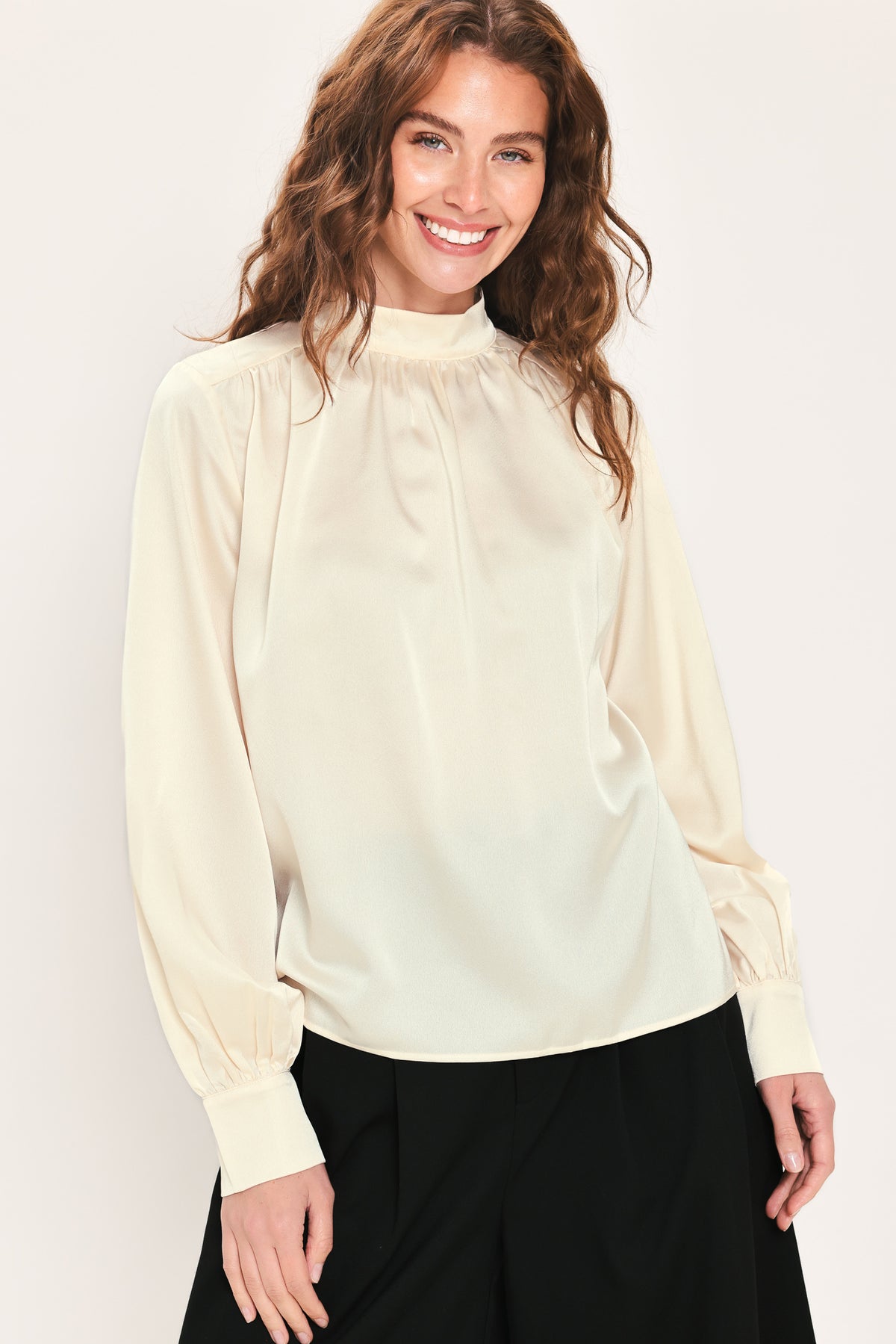 Woman wearing a long sleeve mock neck cream beige blouse | Flying Tomato
