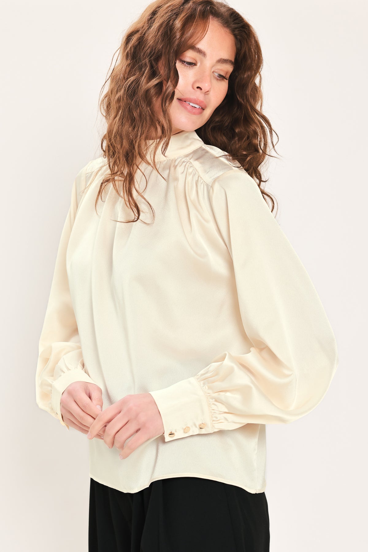 Woman wearing a long sleeve mock neck cream beige blouse | Flying Tomato