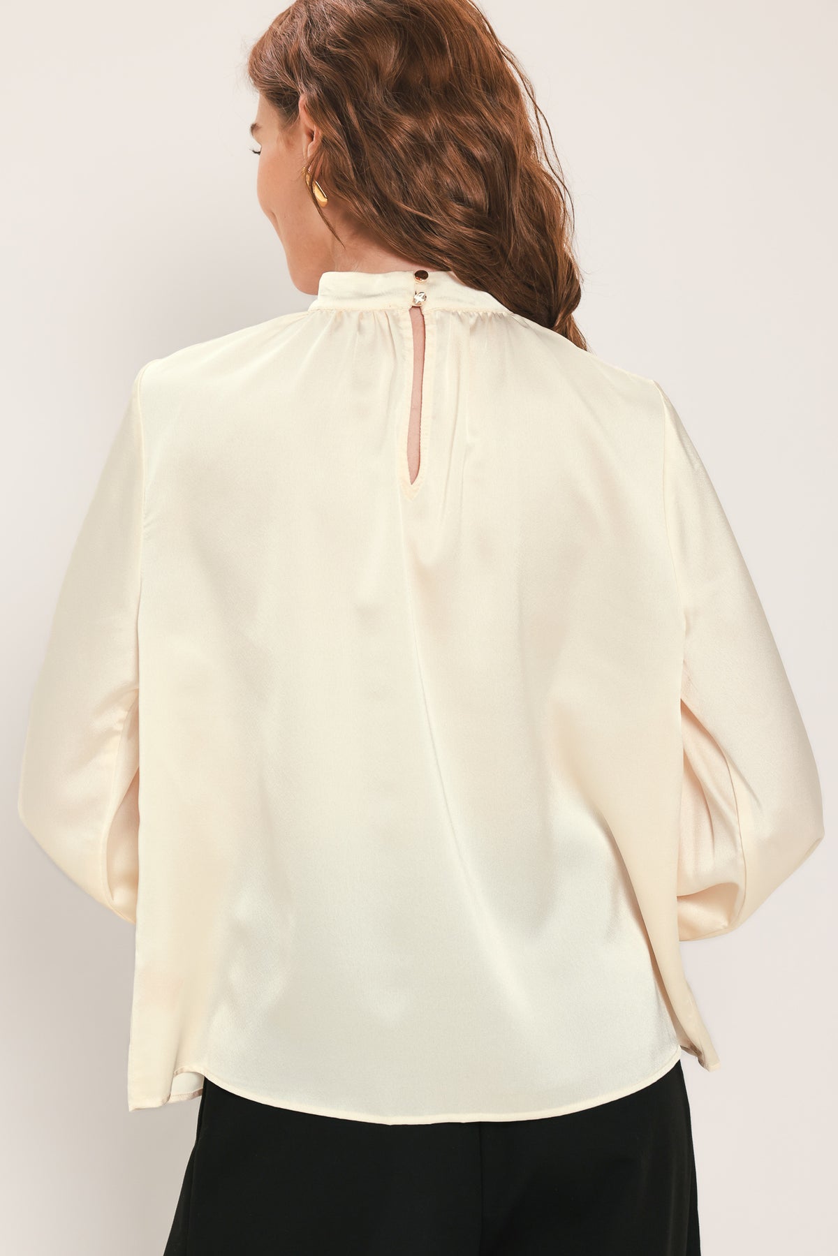 Woman wearing a long sleeve mock neck cream beige blouse | Flying Tomato