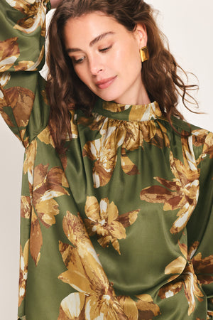 Woman wearing an olive green long sleeve top with a mock neckline and brown floral print | Flying Tomato