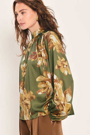 Woman wearing an olive green long sleeve top with a mock neckline and brown floral print | Flying Tomato