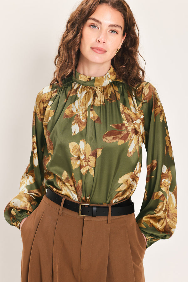 Woman wearing an olive green long sleeve top with a mock neckline and brown floral print | Flying Tomato