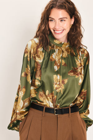 Woman wearing an olive green long sleeve top with a mock neckline and brown floral print | Flying Tomato
