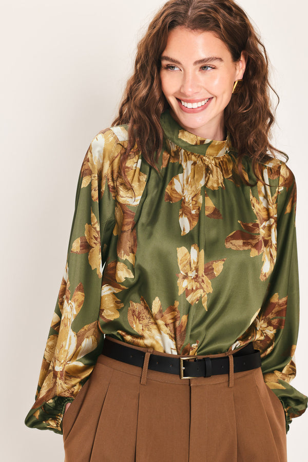 Woman wearing an olive green long sleeve top with a mock neckline and brown floral print | Flying Tomato