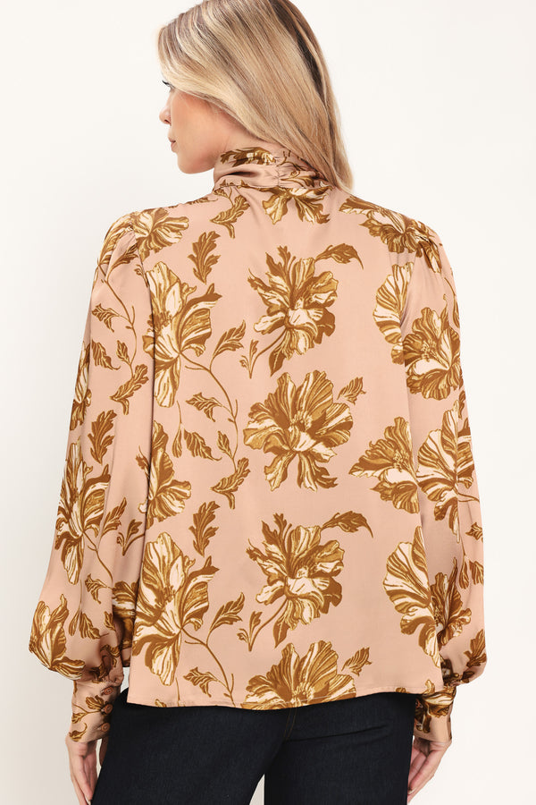 Woman wearing a long sleeve mauve top with a beige floral print and bow around the neck | Flying Tomato