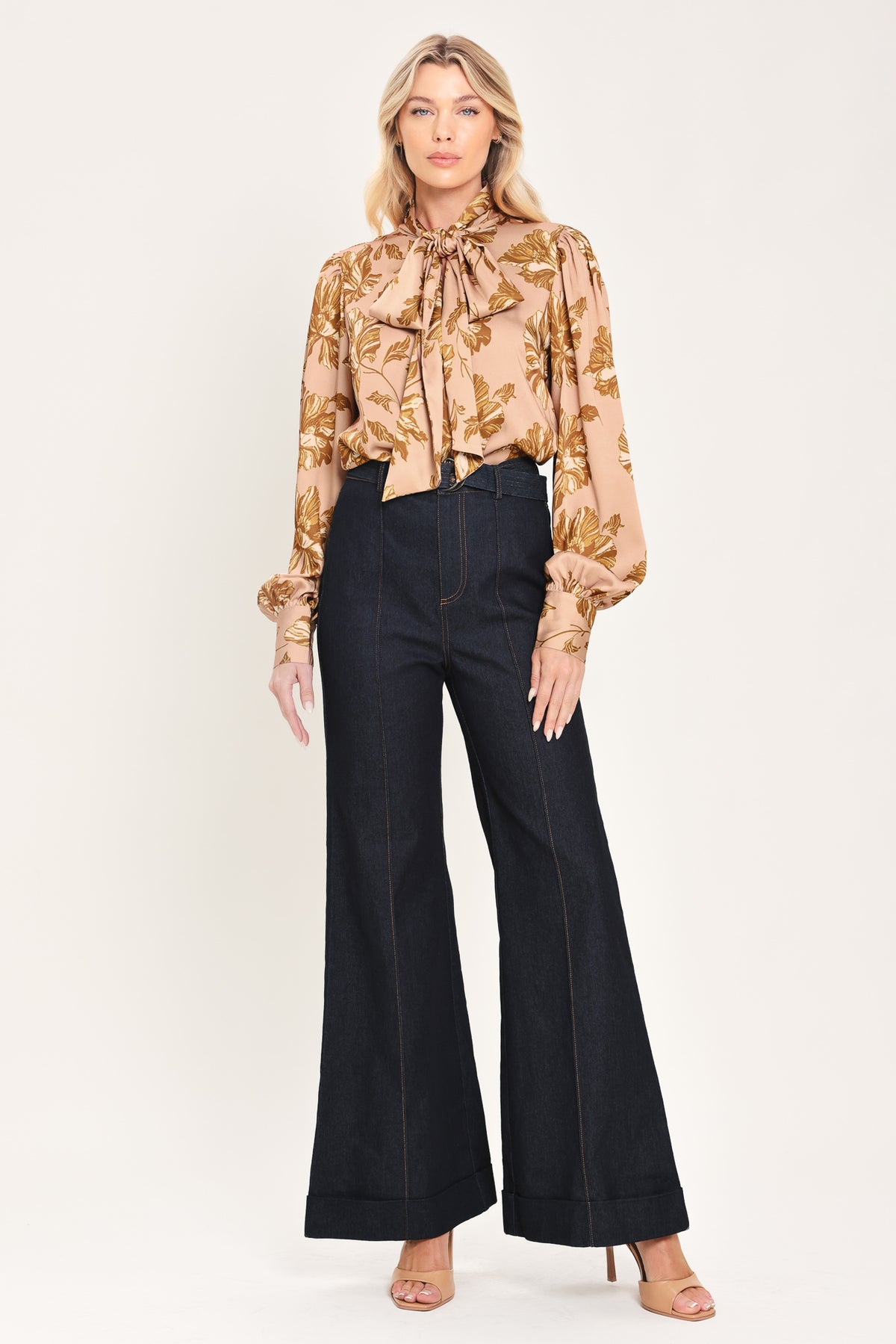 Woman wearing a long sleeve mauve top with a beige floral print and bow around the neck | Flying Tomato