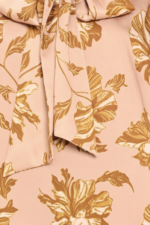 Woman wearing a long sleeve mauve top with a beige floral print and bow around the neck | Flying Tomato