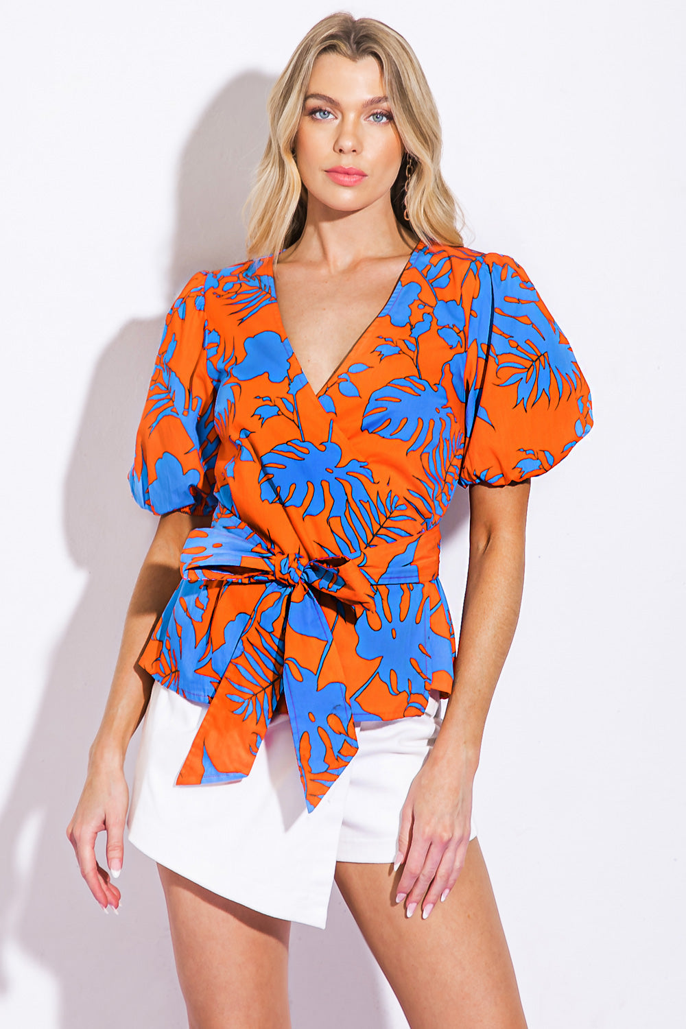 A printed woven top featuring short sleeve and true wrap with ties
