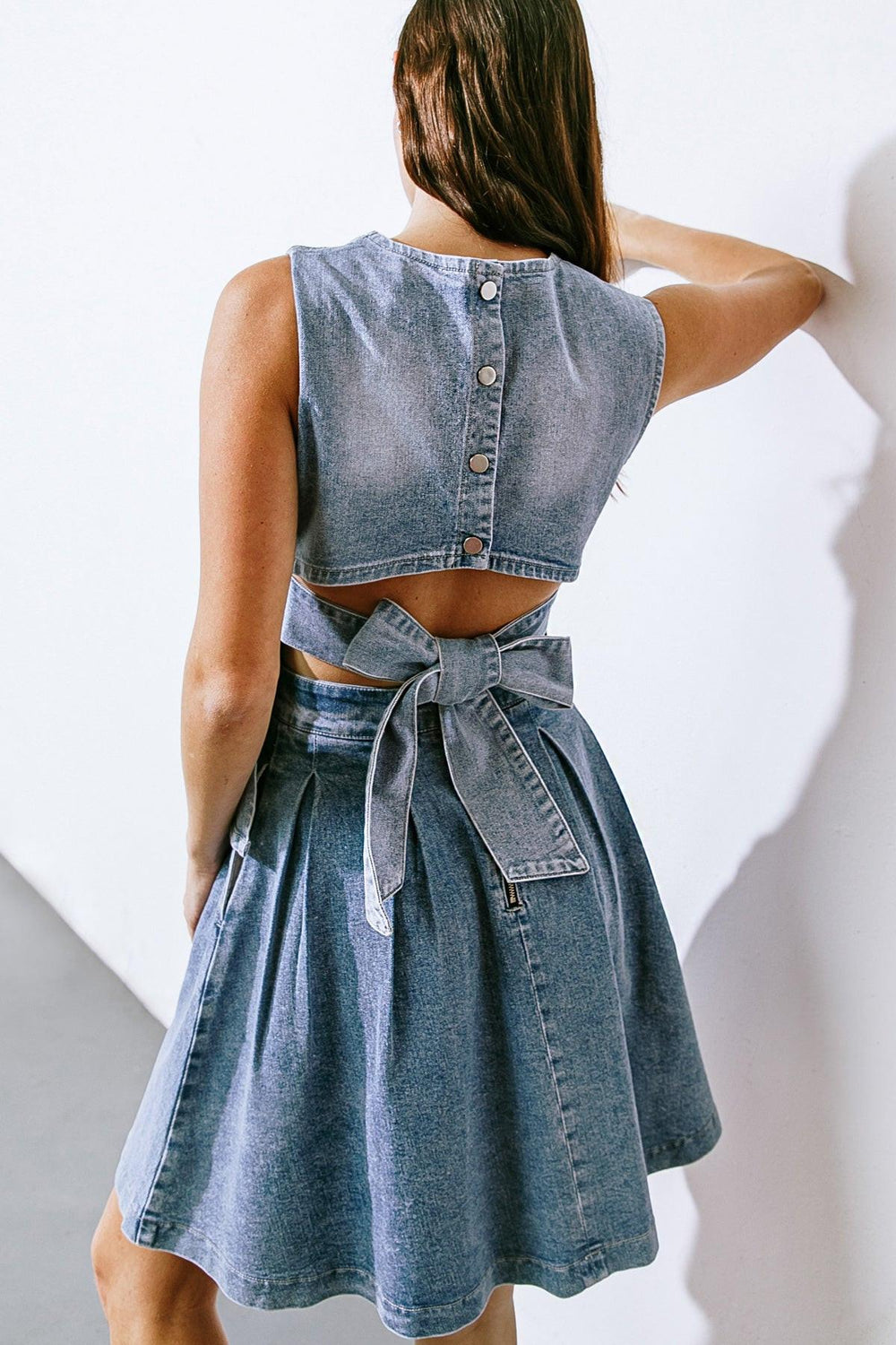 Experience exquisite style with our washed denim top, boasting a round neckline, sleeveless design, and back button down/tie closure.